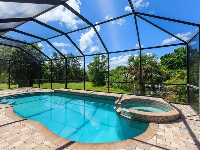 View of pool with a pool with connected hot tub, glass enclosure, and a patio