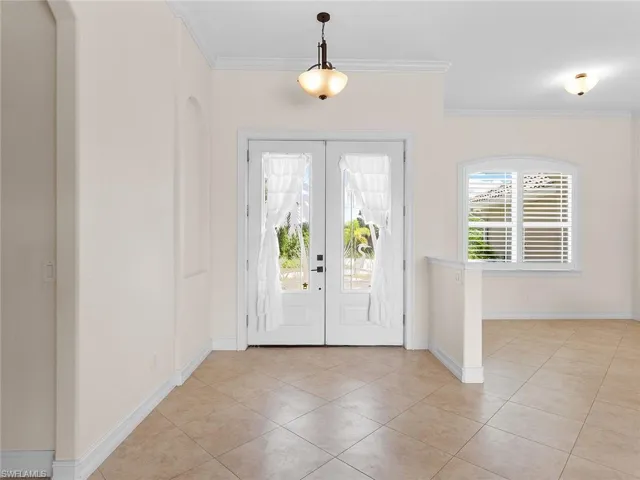 Foyer entrance featuring ornamental molding, french doors, baseboards, and light tile patterned floors