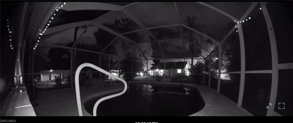 Pool at night featuring an outdoor pool and glass enclosure
