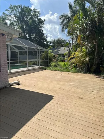 Wooden terrace featuring an outdoor pool and a lanai