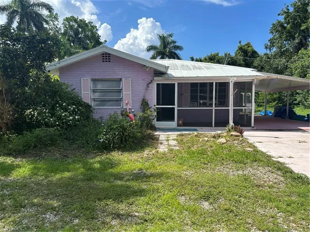 Single story home featuring a sunroom, an attached carport, a front yard, and concrete driveway