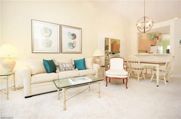 Living room featuring lofted ceiling, an inviting chandelier, and carpet floors
