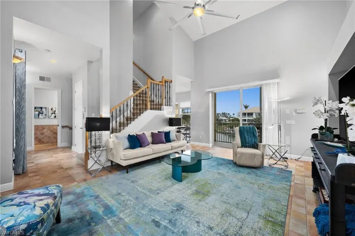 Living room with high vaulted ceiling, ceiling fan, and light tile patterned flooring