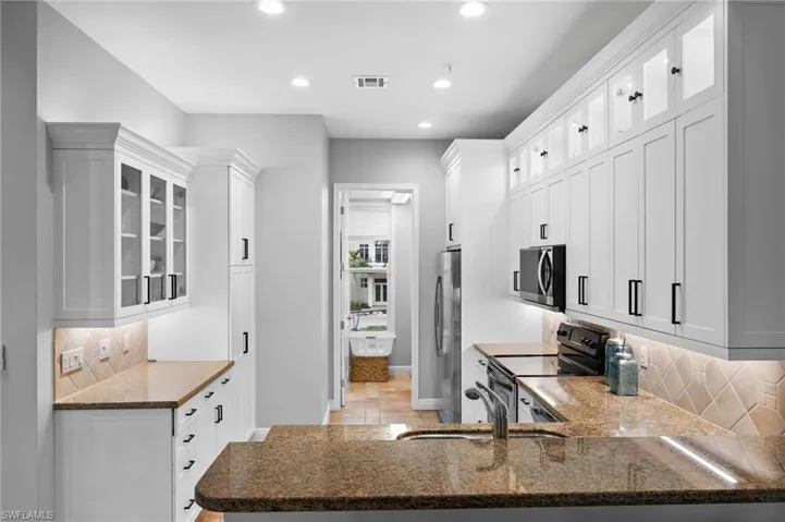 Kitchen with white cabinets, kitchen peninsula, and stainless steel appliances