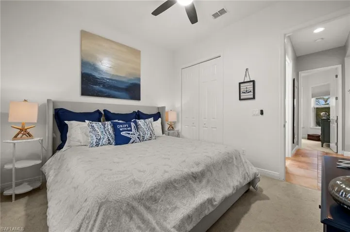 Carpeted bedroom featuring ceiling fan and a closet