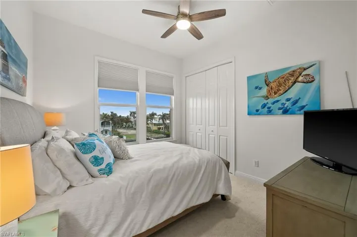 Carpeted bedroom featuring ceiling fan and a closet