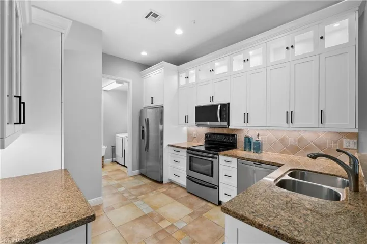 Kitchen featuring washer and dryer, sink, white cabinetry, and stainless steel appliances