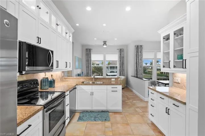 Kitchen with stainless steel appliances, white cabinetry, kitchen peninsula, and tasteful backsplash