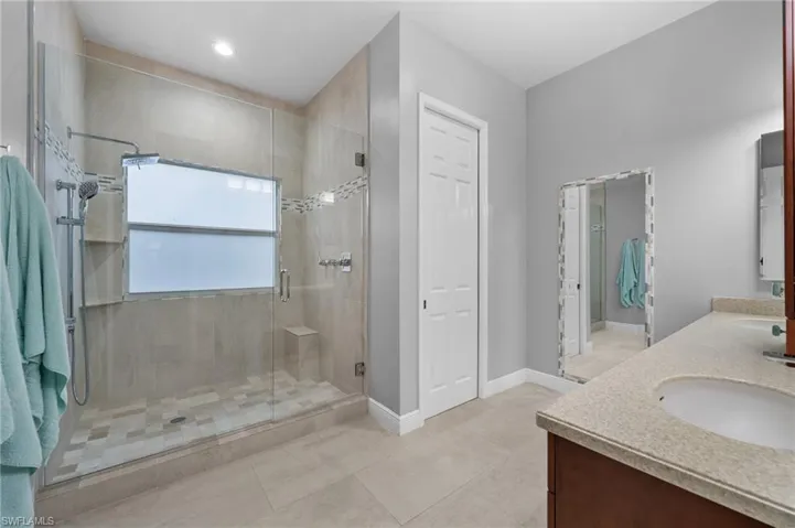 Bathroom with a shower with door, tile patterned floors, and vanity