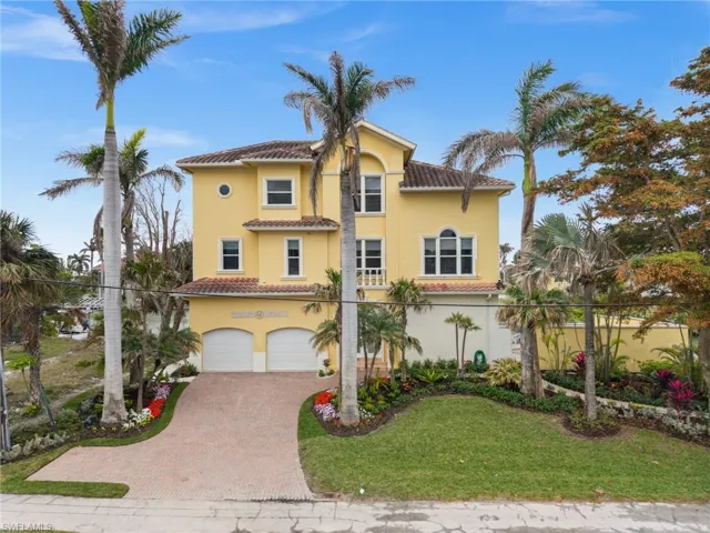 Mediterranean / spanish home featuring a garage and a front lawn