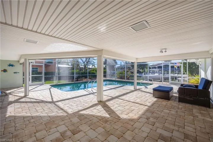 Swimming pool featuring a sunroom, a patio, and glass enclosure