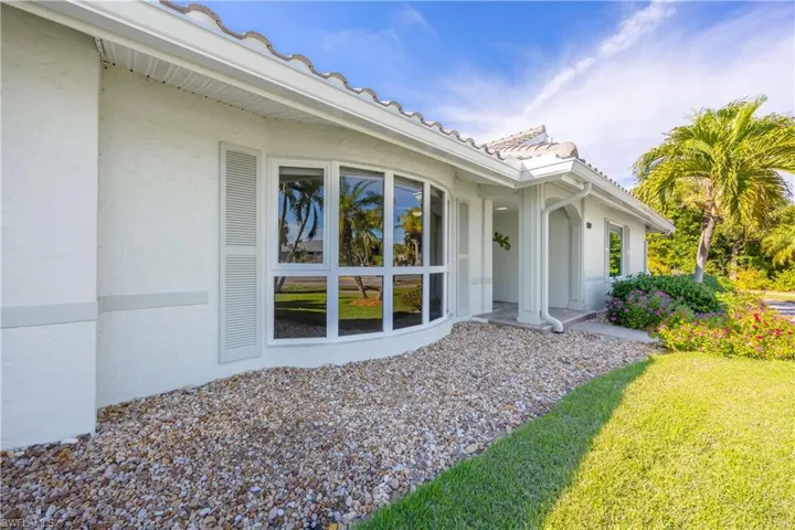 Back of house featuring stucco siding, a yard, and a tiled roof