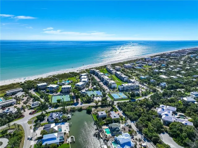 View of property location featuring waterfront with a beach and nearby suburban area