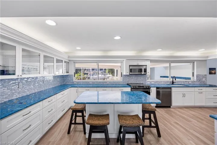 Kitchen with white cabinetry, a kitchen breakfast bar, a kitchen island, dark stone counters, and recessed lighting