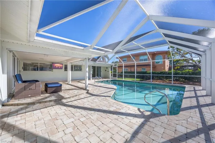 Outdoor pool featuring a patio area, a sunroom, and glass enclosure