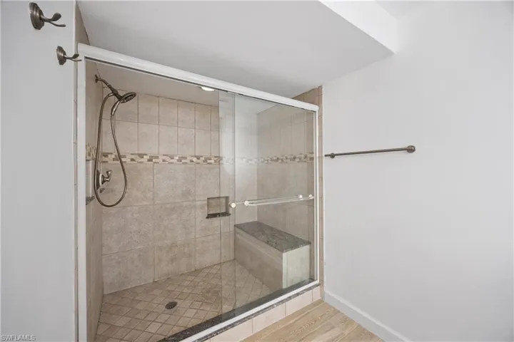 Unfurnished bedroom featuring a barn door, connected bathroom, light wood finished floors, and ceiling fan
