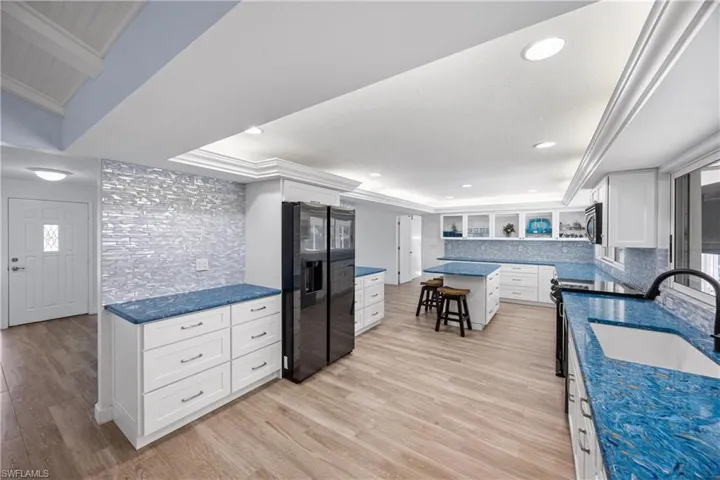 Kitchen with white cabinetry, a breakfast bar area, light wood-type flooring, stainless steel appliances, and recessed lighting