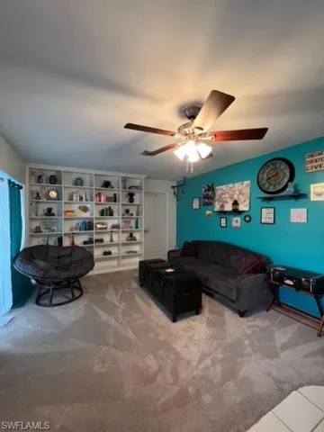 Carpeted living room featuring ceiling fan