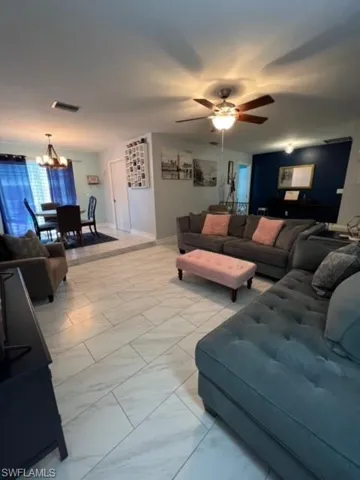Living room featuring light tile floors and ceiling fan with notable chandelier