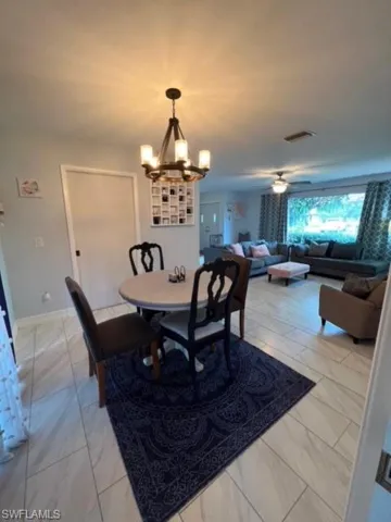Dining area featuring ceiling fan with notable chandelier and light tile flooring