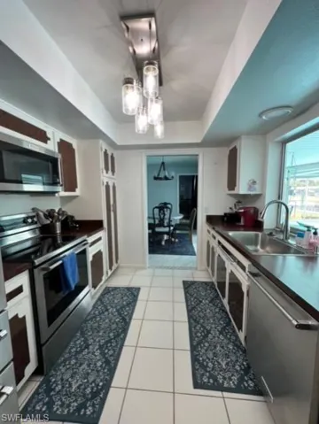 Kitchen with a raised ceiling, stainless steel appliances, and white cabinets