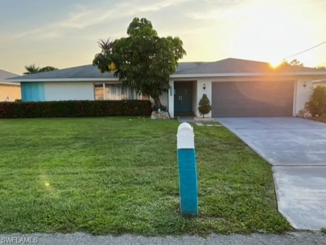 Single story home with a garage and a yard
