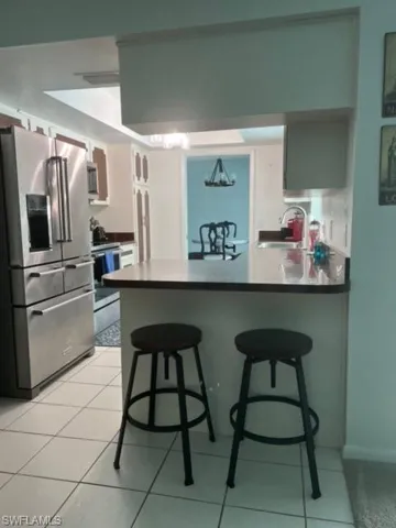 Kitchen featuring refrigerator, sink, light tile floors, and kitchen peninsula