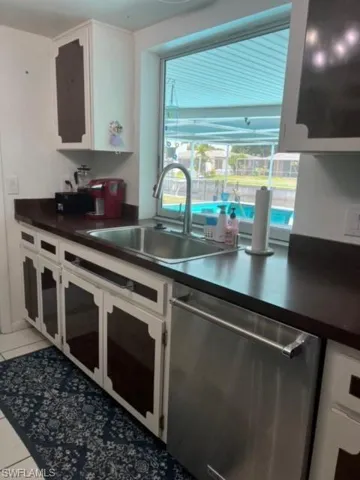 Kitchen with sink, white cabinets, tile floors, oven, and dishwasher