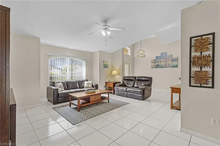 Tiled living room with ceiling fan with notable chandelier