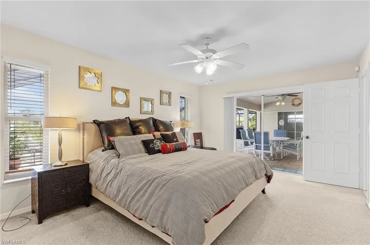 Bedroom featuring multiple windows, access to exterior, ceiling fan, and carpet flooring