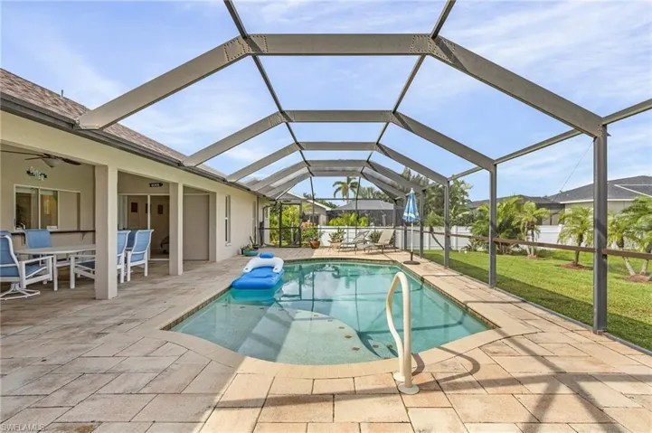 View of pool with glass enclosure, ceiling fan, a lawn, and a patio
