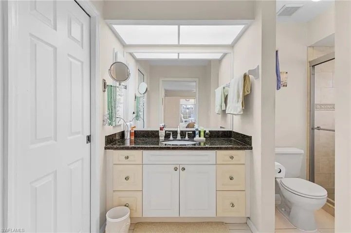 Bathroom with tile patterned flooring, vanity, toilet, and a shower with shower door