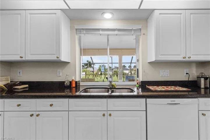 Kitchen featuring white cabinetry, white dishwasher, and sink