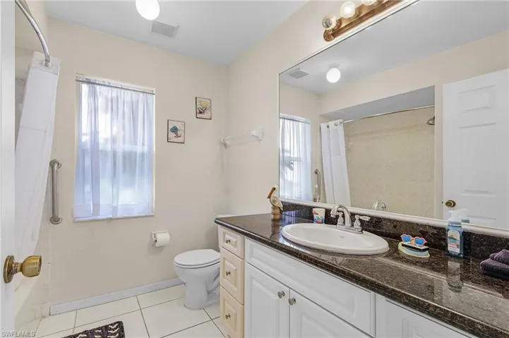 Bathroom featuring curtained shower, tile patterned flooring, toilet, and vanity