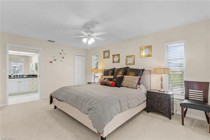 Carpeted bedroom featuring a closet, ceiling fan, and ensuite bathroom