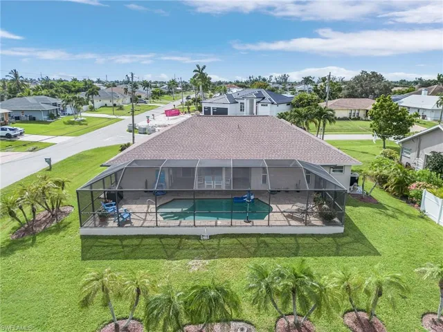 Rear view of property with a lawn and a lanai