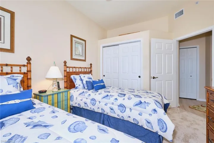 Bedroom featuring visible vents, light carpet, and a closet