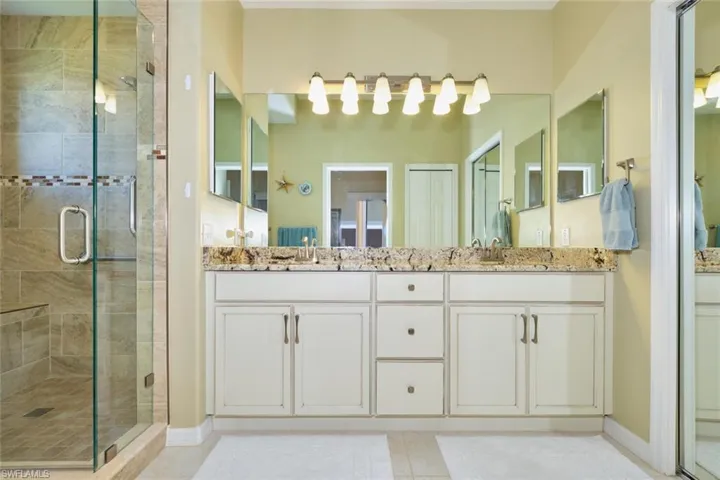 Bathroom featuring a sink, a stall shower, and double vanity
