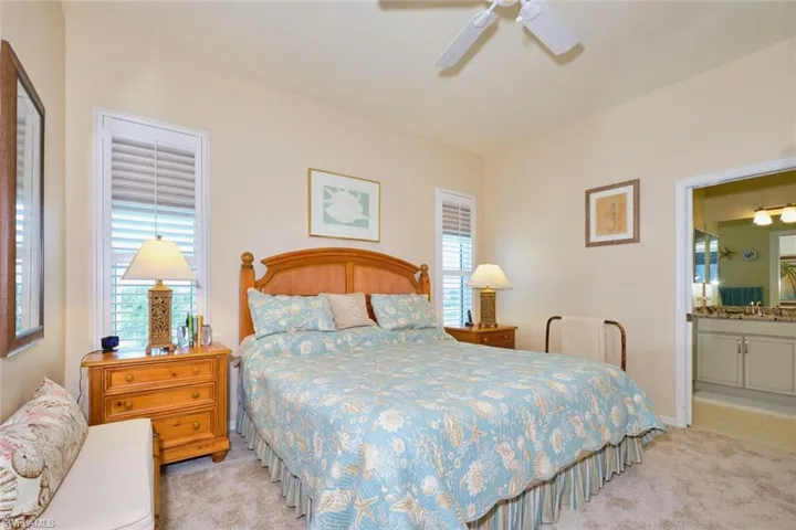 Carpeted bedroom with connected bathroom, baseboards, and ceiling fan