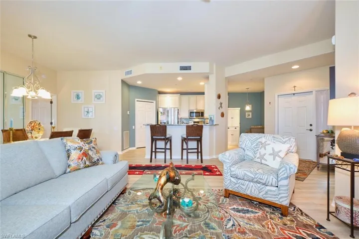 Living room with visible vents, light wood-style floors, and a chandelier