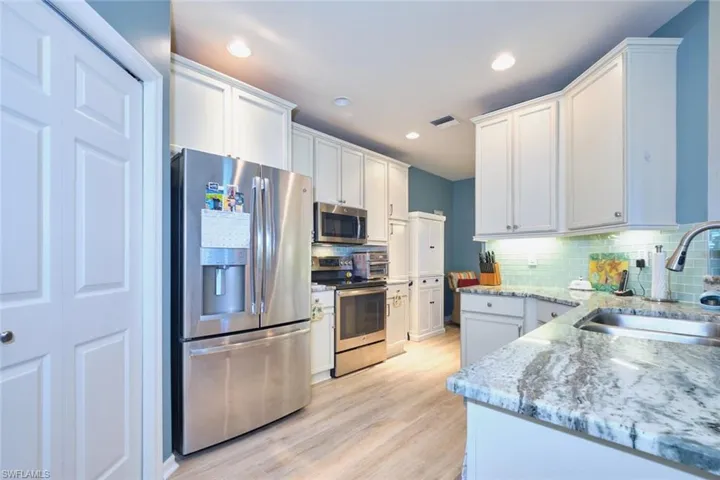 Kitchen featuring visible vents, light wood-style flooring, a sink, stainless steel appliances, and backsplash