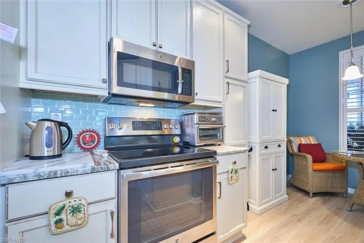Kitchen featuring decorative backsplash, light wood-style floors, white cabinetry, and appliances with stainless steel finishes