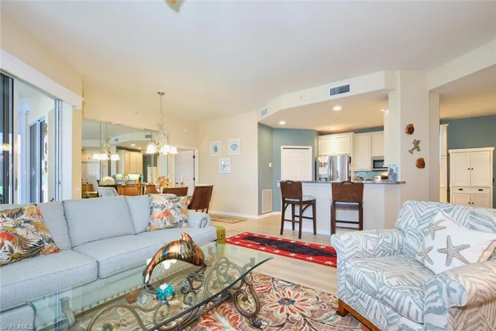 Living room featuring light wood-style flooring, baseboards, visible vents, and a chandelier
