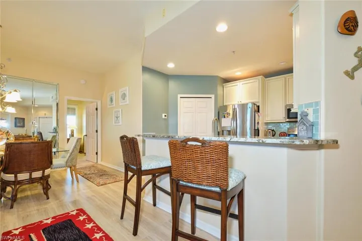 Kitchen featuring backsplash, recessed lighting, light wood-style floors, appliances with stainless steel finishes, and a breakfast bar area