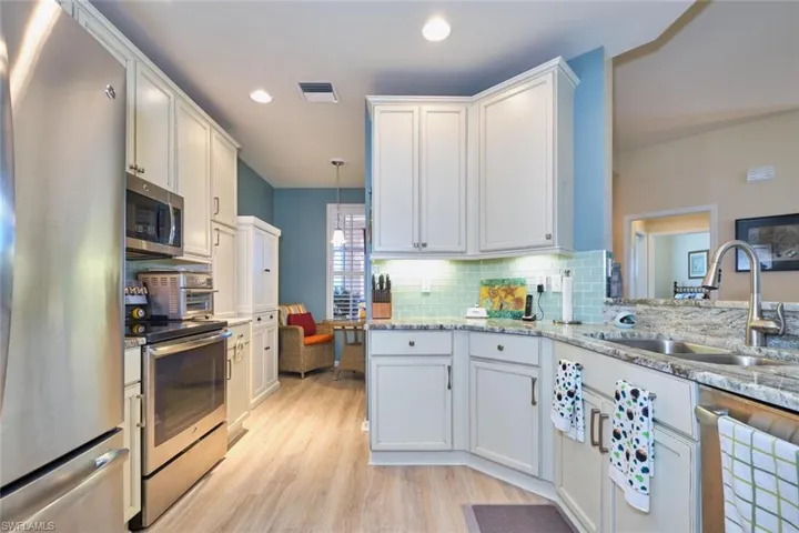 Kitchen featuring visible vents, decorative backsplash, light wood-style floors, stainless steel appliances, and a sink
