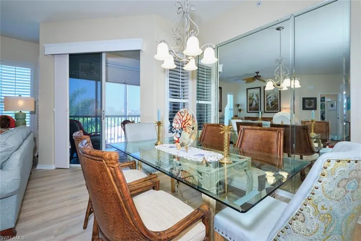 Dining room with a wealth of natural light, ceiling fan with notable chandelier, light wood finished floors, and baseboards