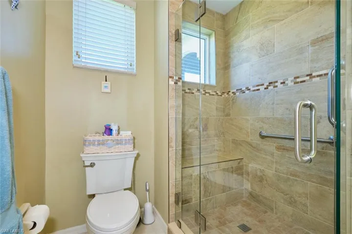 Bathroom featuring a stall shower, toilet, and baseboards