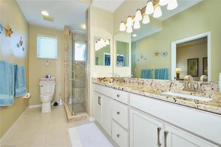Bathroom featuring tile patterned floors, visible vents, toilet, a stall shower, and a sink