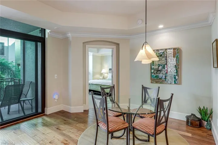 Dining area featuring wood-finish flooring, crown molding, and a tray ceiling