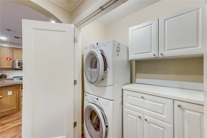 Dedicated laundry area featuring stacked appliances and white cabinetry